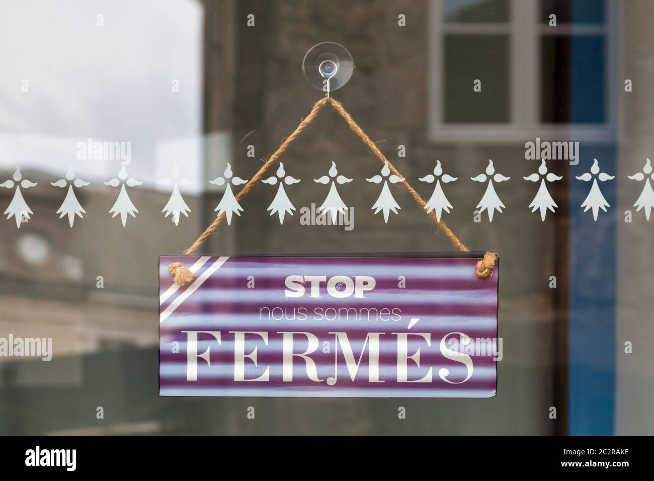 Sign hanging at the glass door of a shop saying in French (Stop, nous sommes fermés), meaning in English (Stop, we are closed). Stock Photo