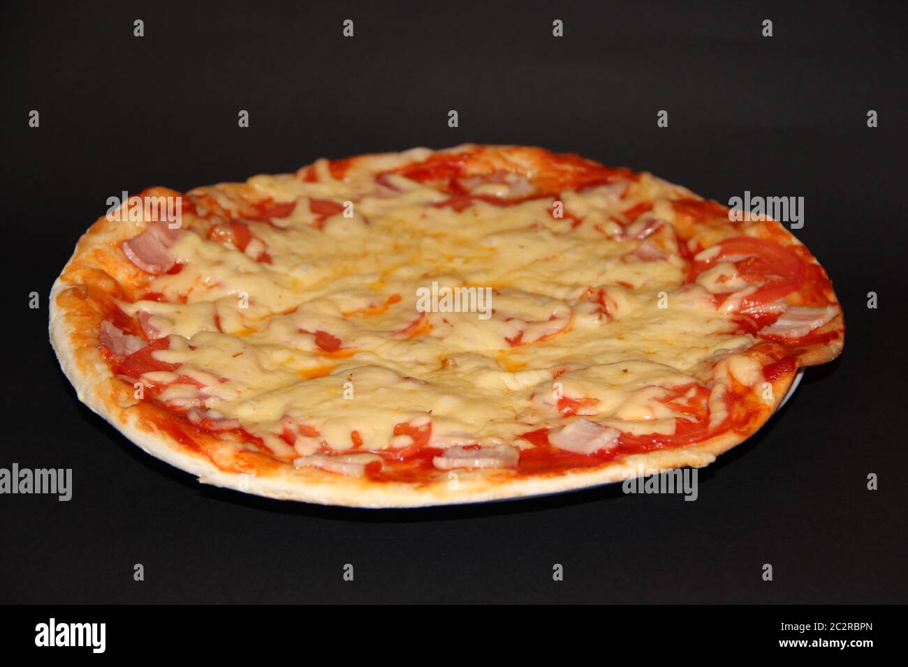 Fresh appetizing pizza with delicious ingredients isolated on black background. Tasty pizza on plate Stock Photo