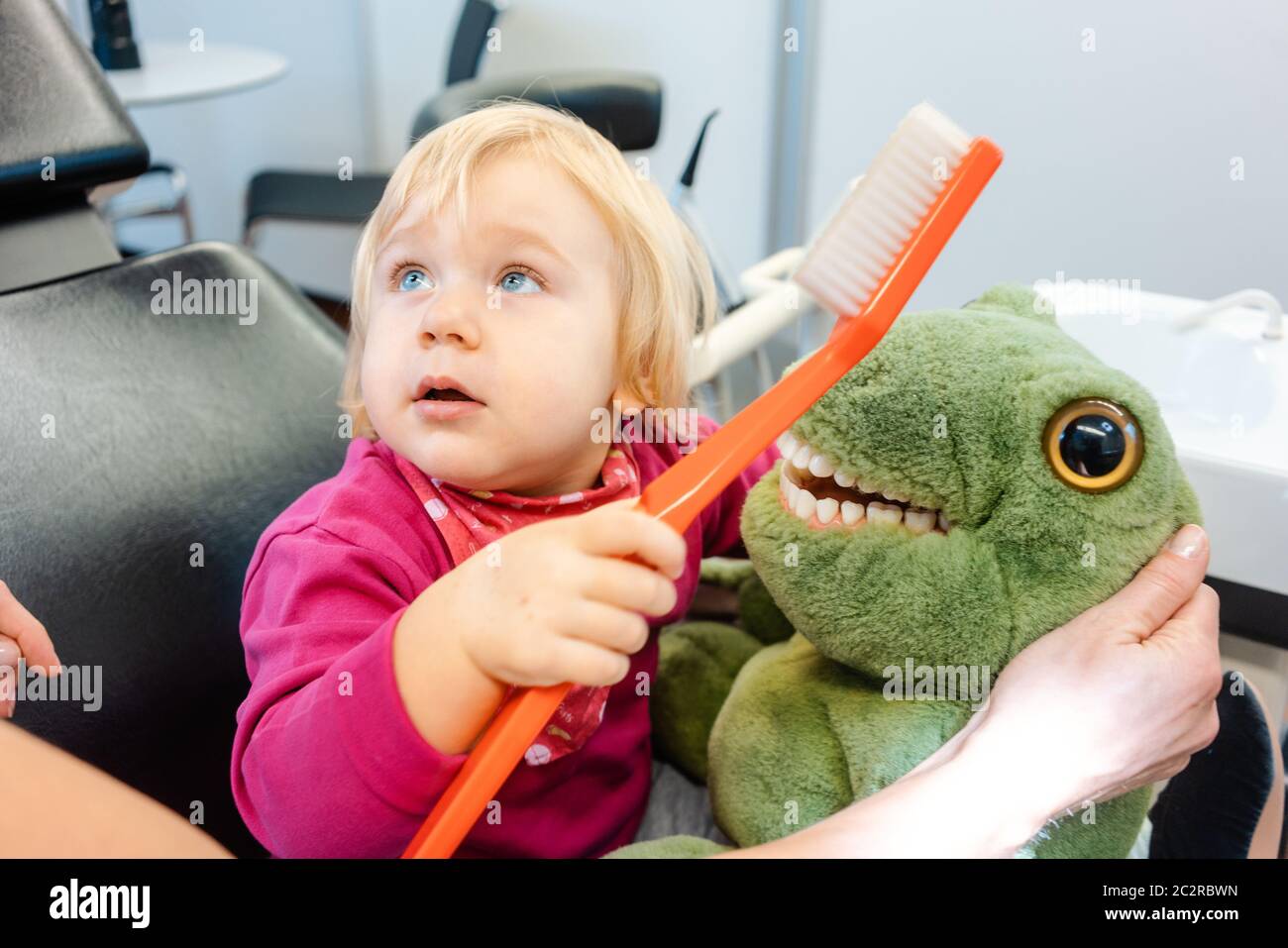 Child at the dentist brushing teeth of a plush toy learning how to do