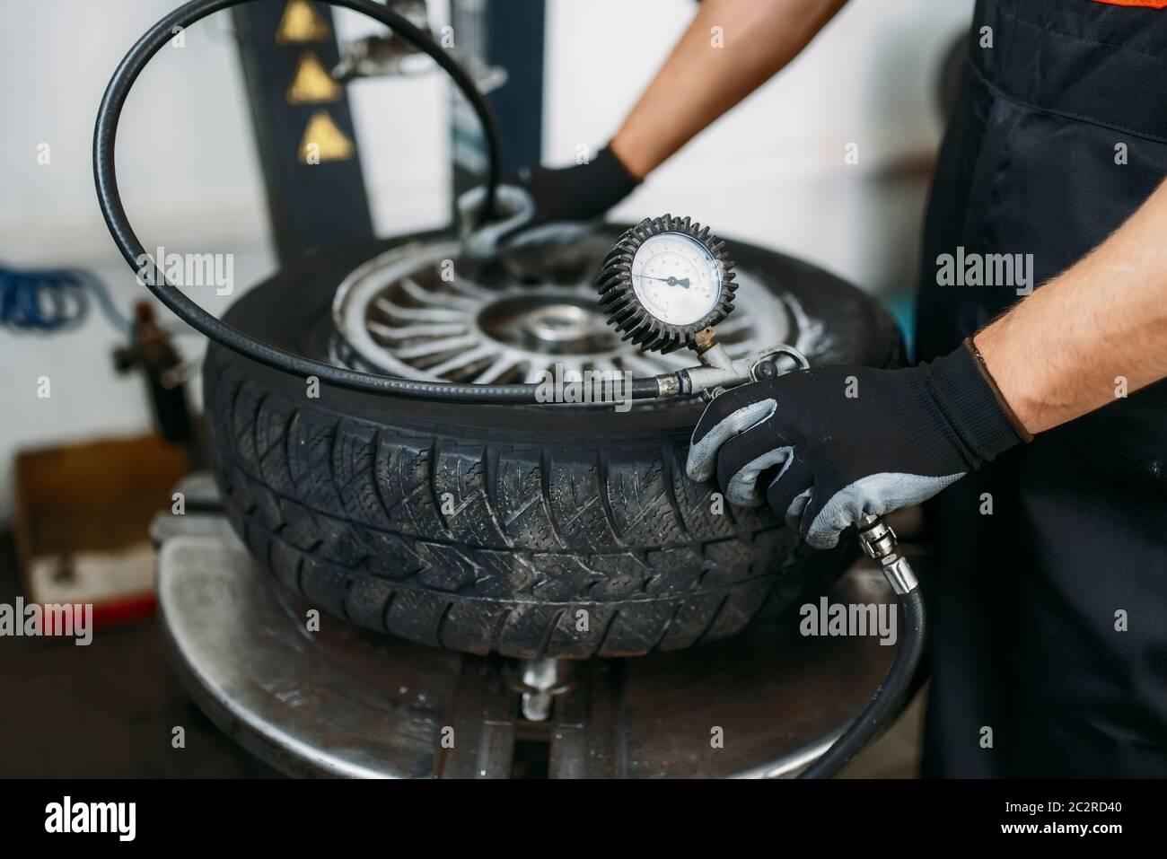 Mechanic inflates the wheel, tire repairing service. Man repairs car