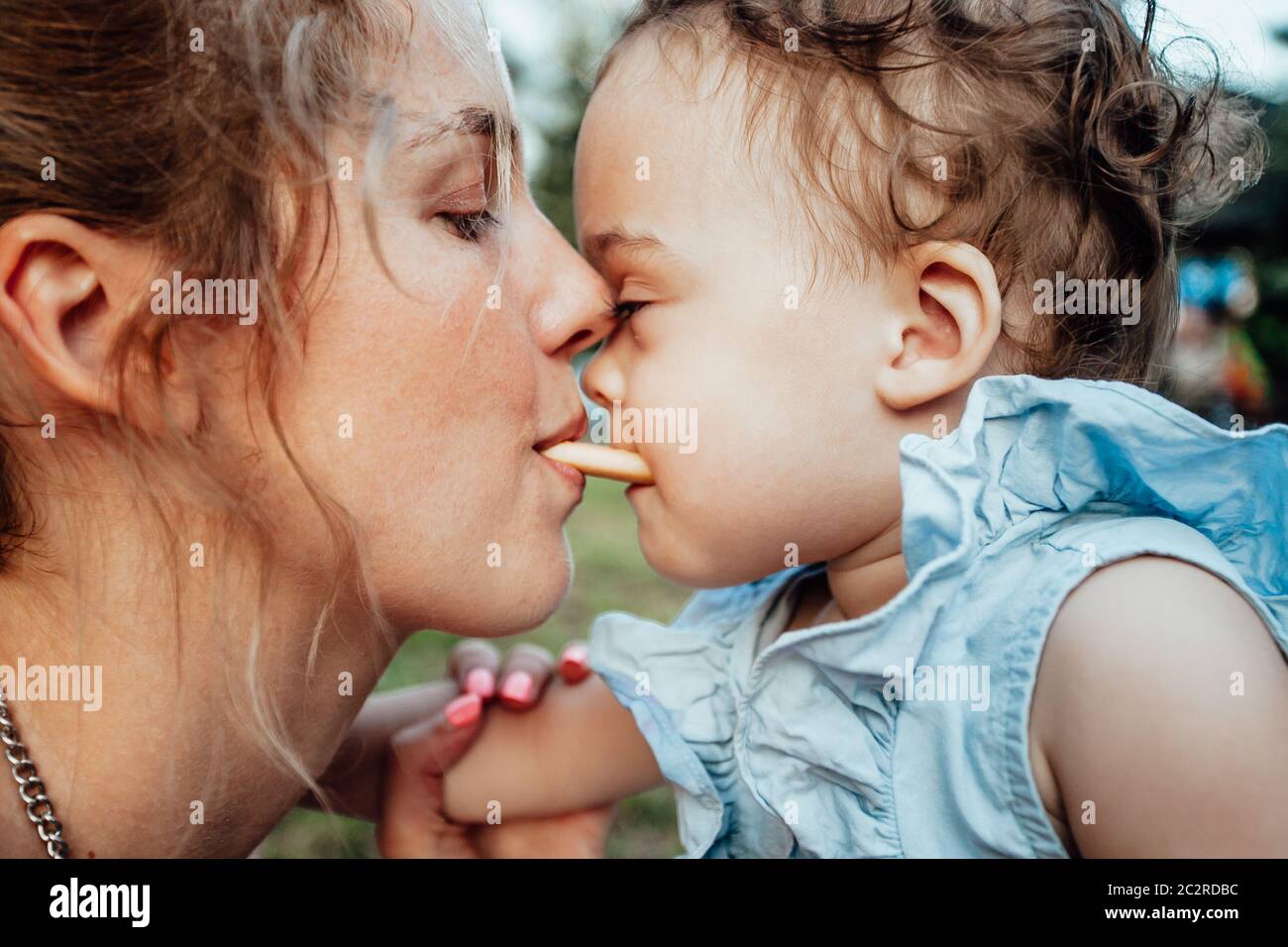 Portrait of a young girl being held by his mother.   Head to head, looking at each other Stock Photo