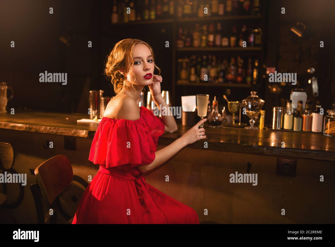 Portrait of young woman in red dress sitting at the bar counter