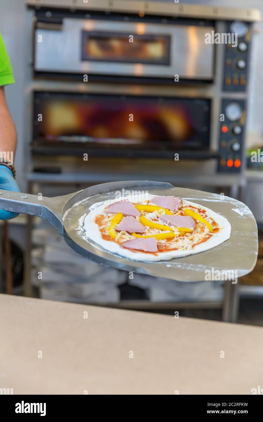 Baker hands with shovel, cooking pizza, electric ovens Stock Photo