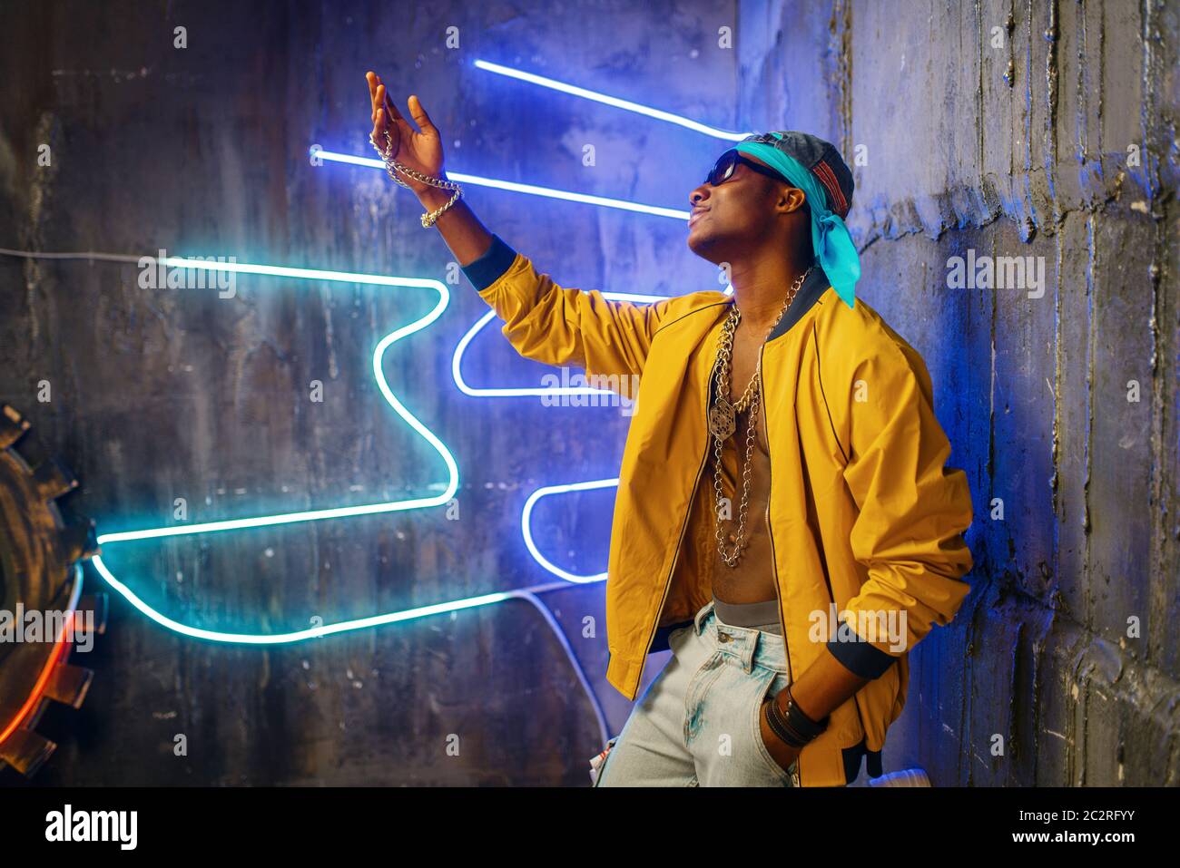 Black rapper in underpass neon light on background. Rap performer in club with grunge walls, underground music Stock Photo