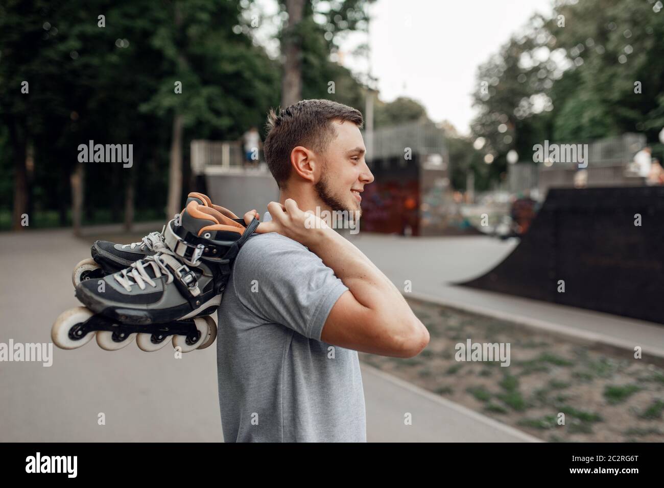 Roller skating, male skater carries skates on his shoulder, back view