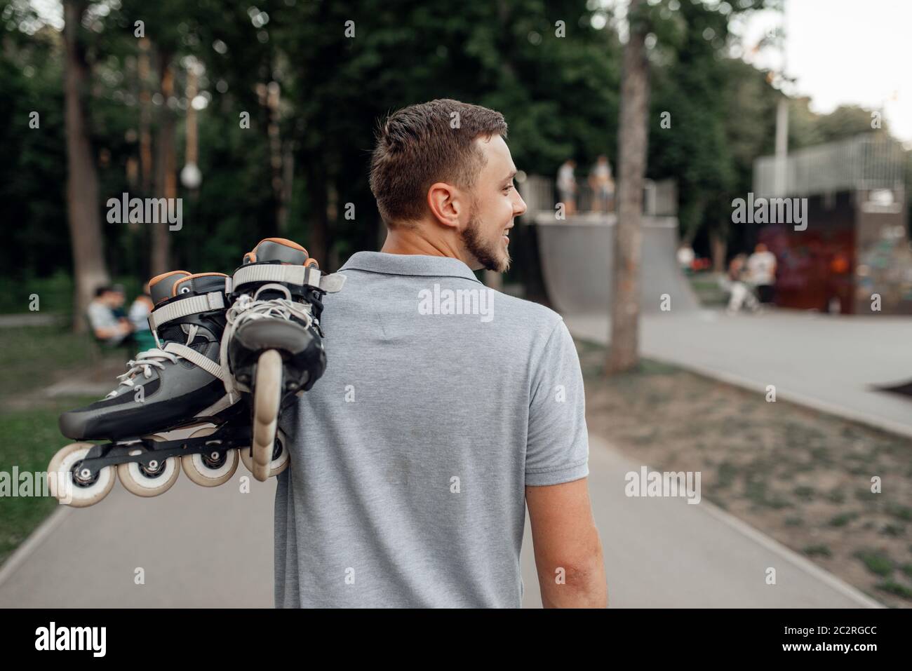 Roller skating, male skater carries skates on his shoulder, back view