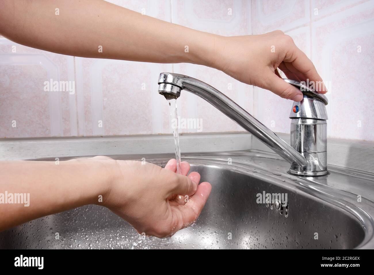 Women's hand turn on a faucet Stock Photo