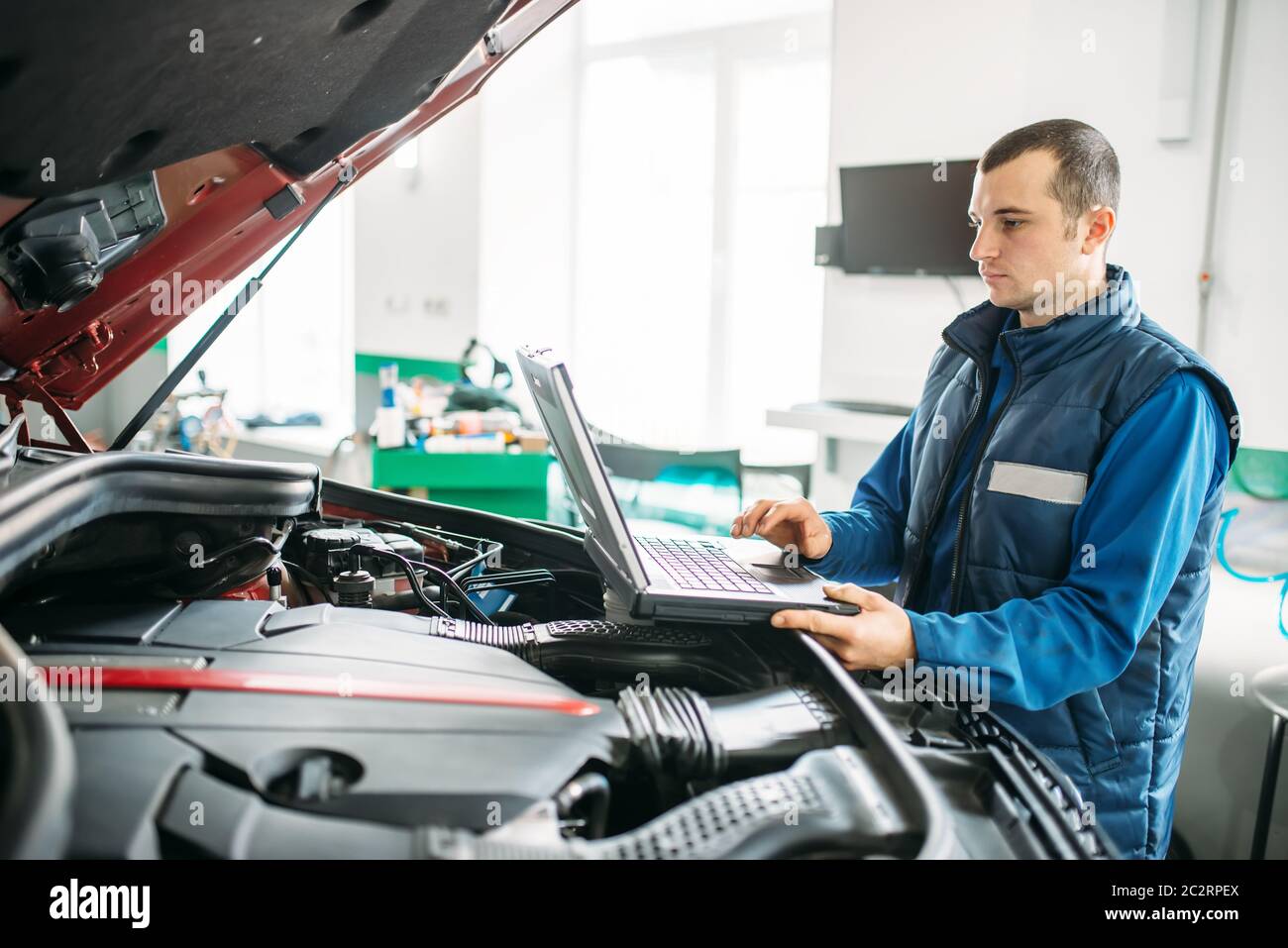 Engineer makes computer diagnostics of the car in autoservice. Vehicle wiring inspection Stock Photo