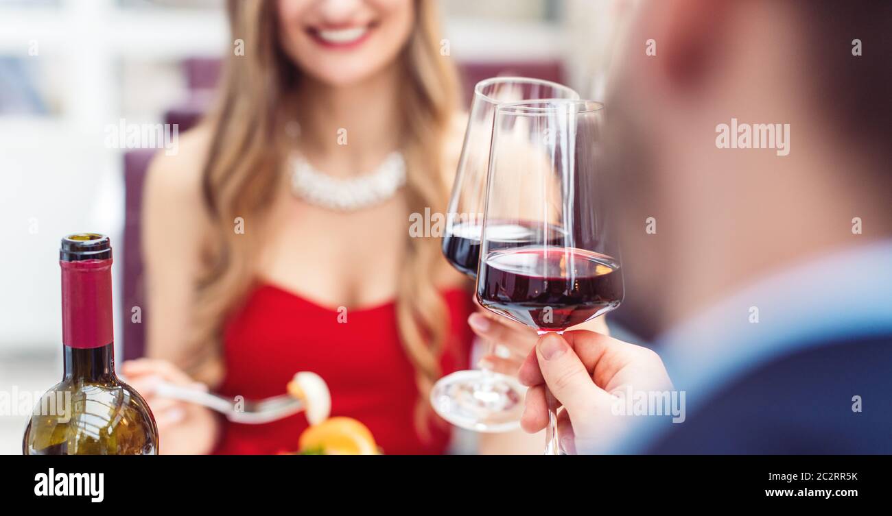 Couple toasting with red wine in romantic restaurant looking at each other Stock Photo