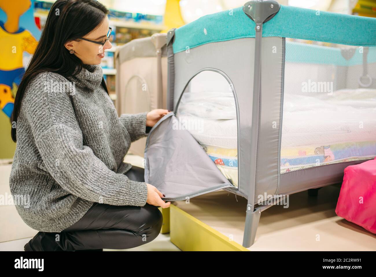 Pregnant woman buying cot in store. Future mother in shop of goods for