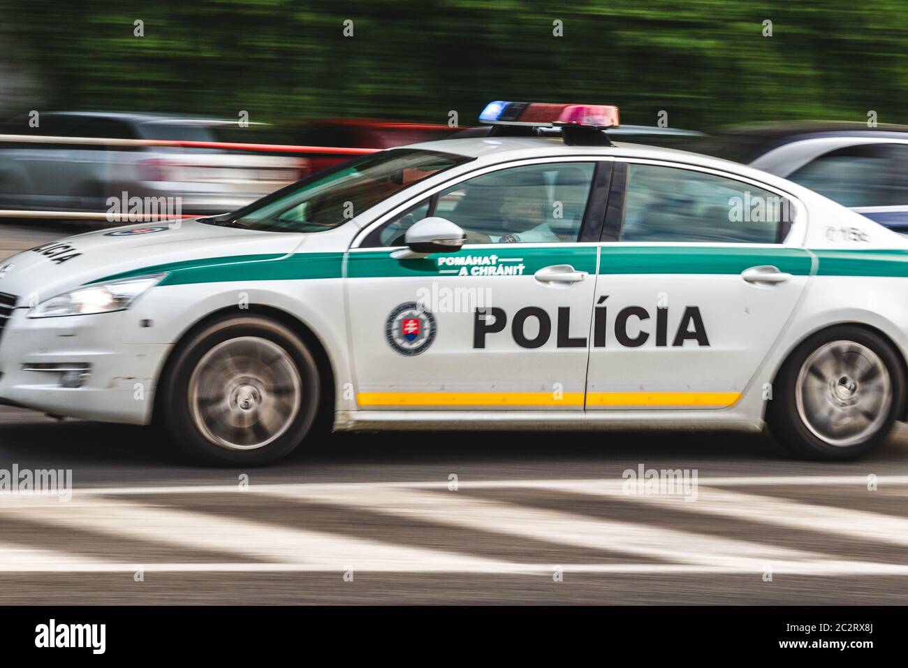 Slovak police officer driving fast police car on street road with blured cars in background with lights on Stock Photo