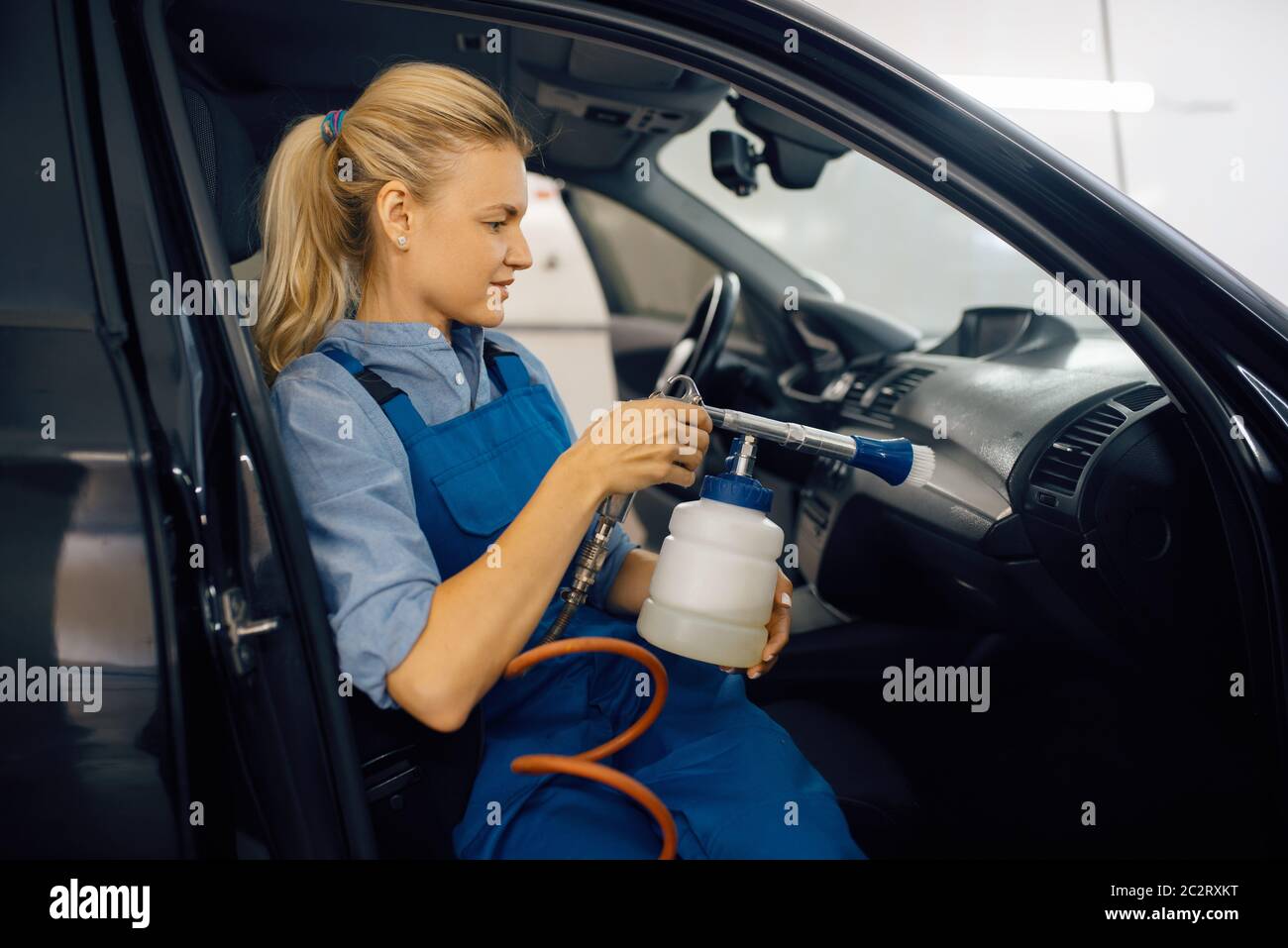 Female washer cleans automobile interior, view through the windshield