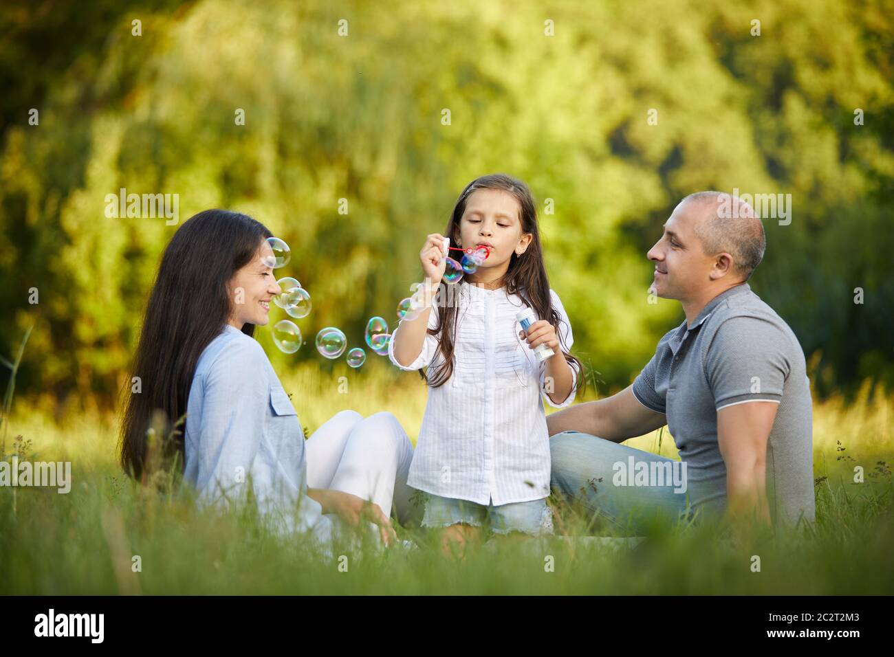 happy family with child girl blow soap bubbles outdoor in sunny day ...