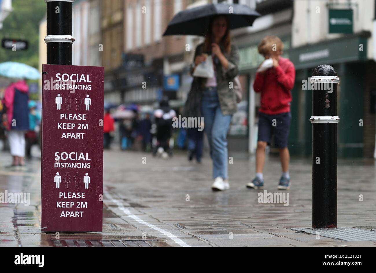 People walk past a social distancing sign on Winchester High street, as ...