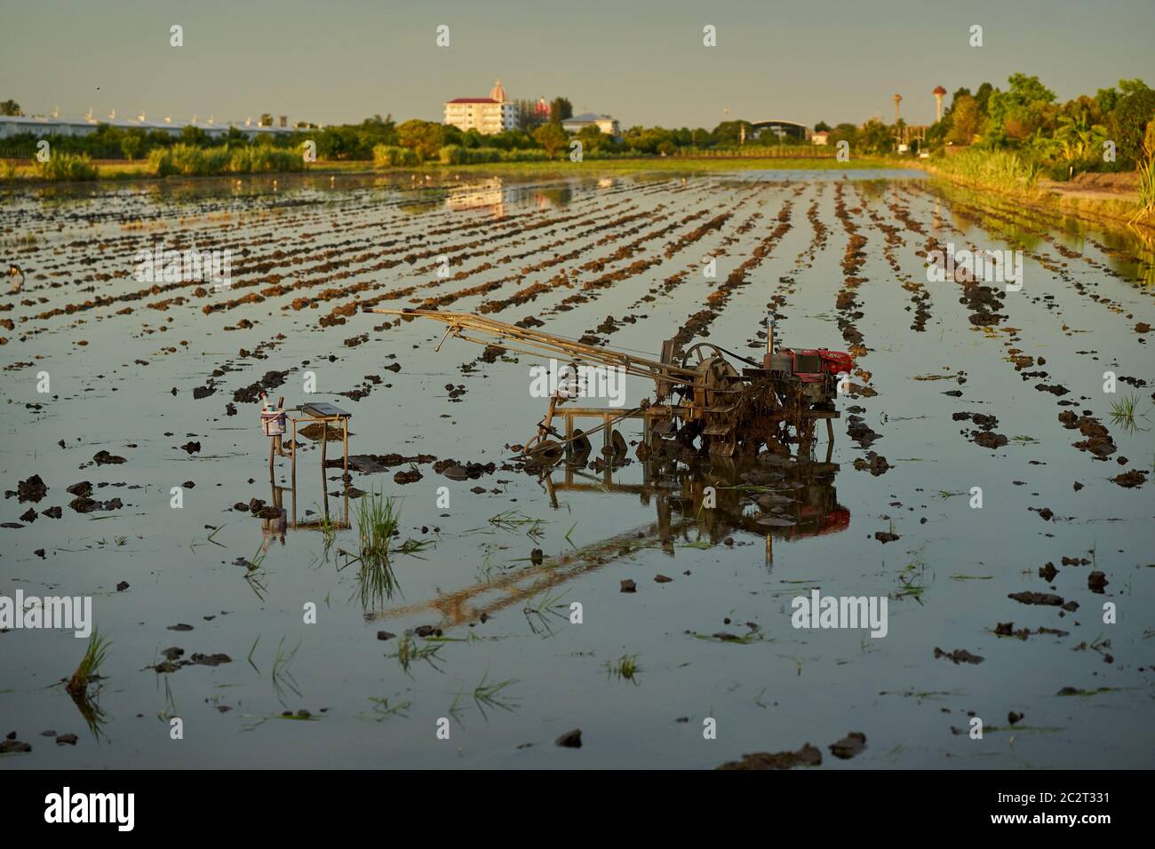 Ploughing machine at rest in a water filled paddy field. Stock Photo