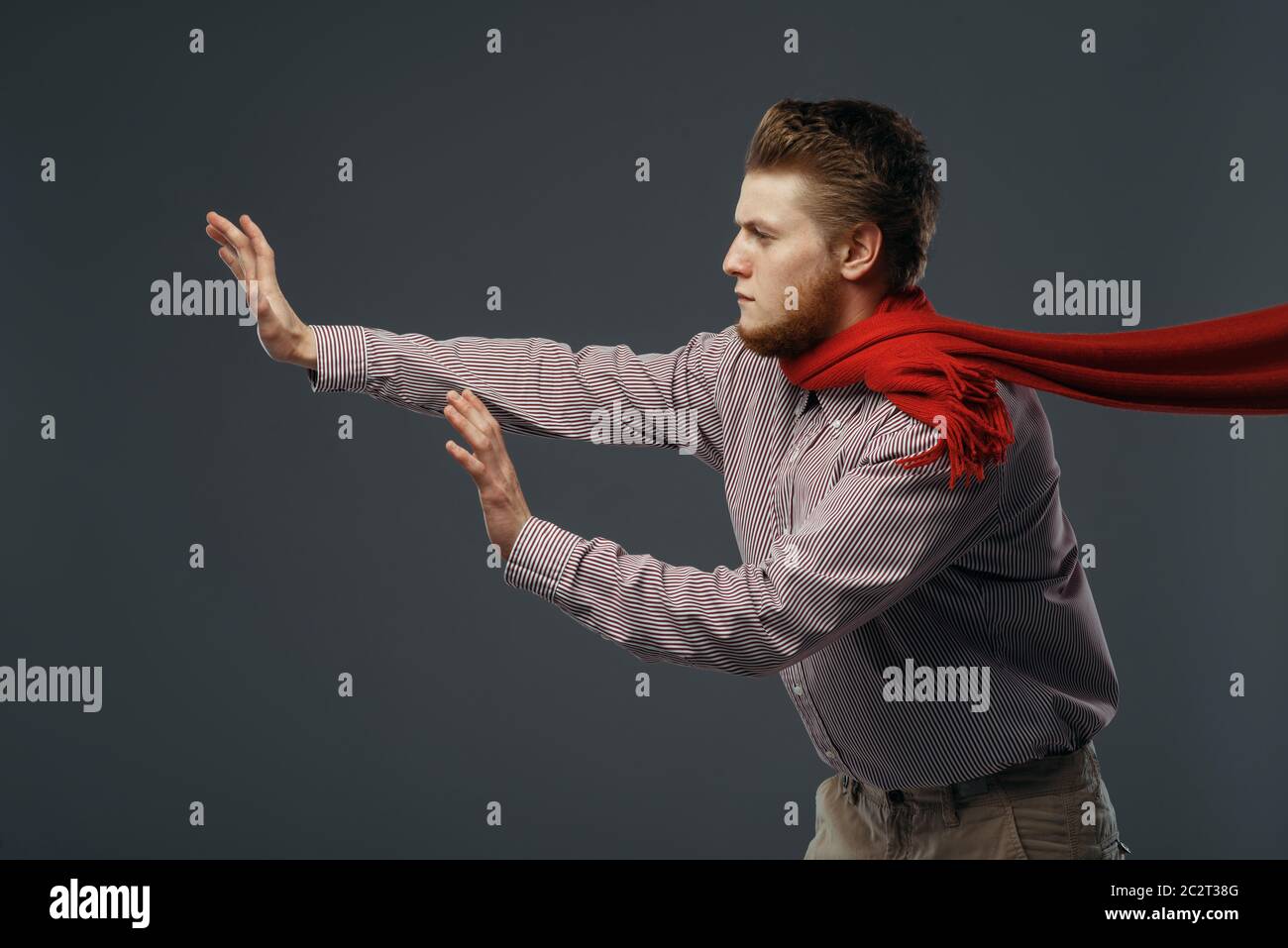 Strong wind blowing on man in red scarf, funny emotion. Powerful air