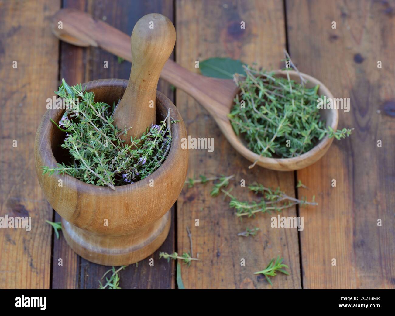 aromatic herb in a woden spoon and mortar on a wooden table Stock Photo
