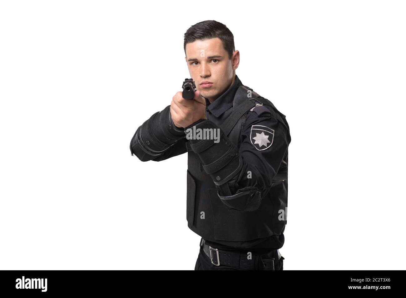Armed police officer aims with a gun, black uniform with body armor, white background, front view. Policeman in special ammunition Stock Photo