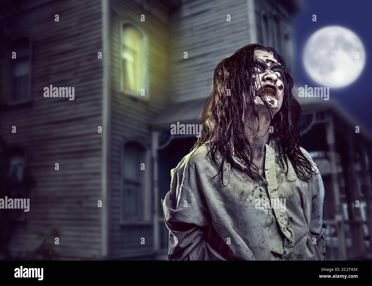 Scary zombie girl near the abandoned house. Horror. Halloween Stock Photo