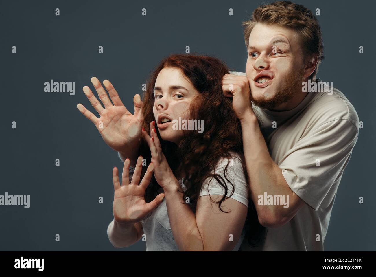Young couple faces crushed on transparent glass, funny emotion. Man and woman with pressed grimaces standing at the showcase, humor, uncomfortable loo Stock Photo