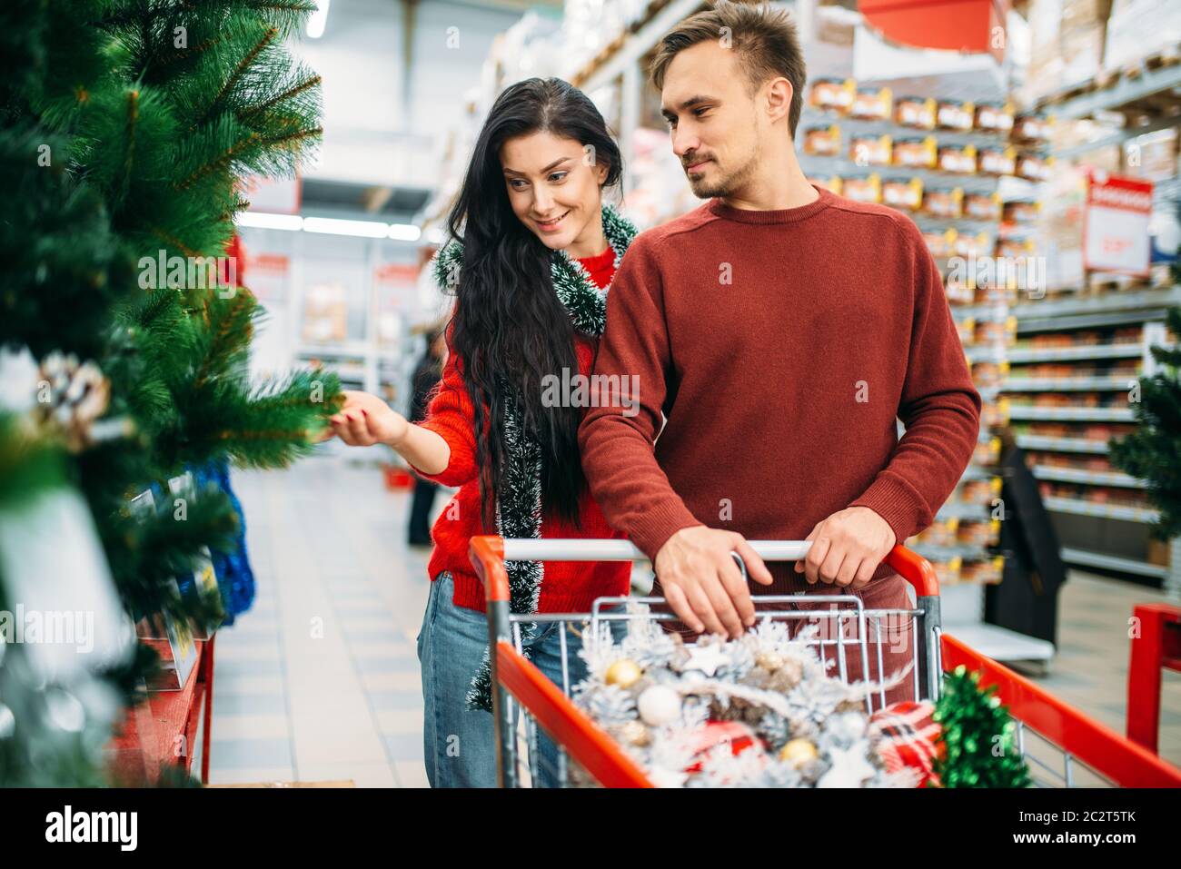 Couple buying christmas tree in supermarket. December shopping