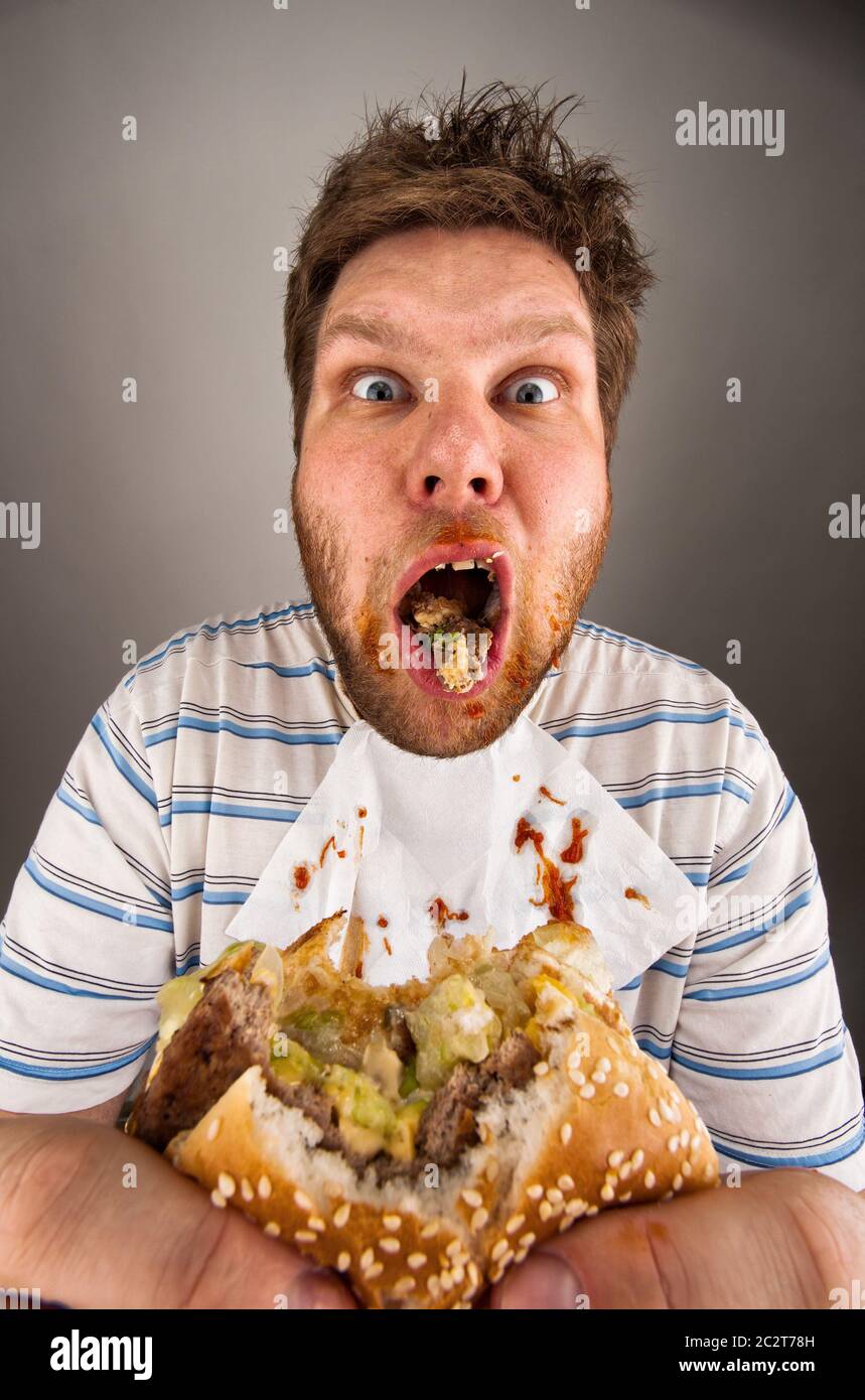 Portrait of surprised dirty man chewing hamburger Stock Photo