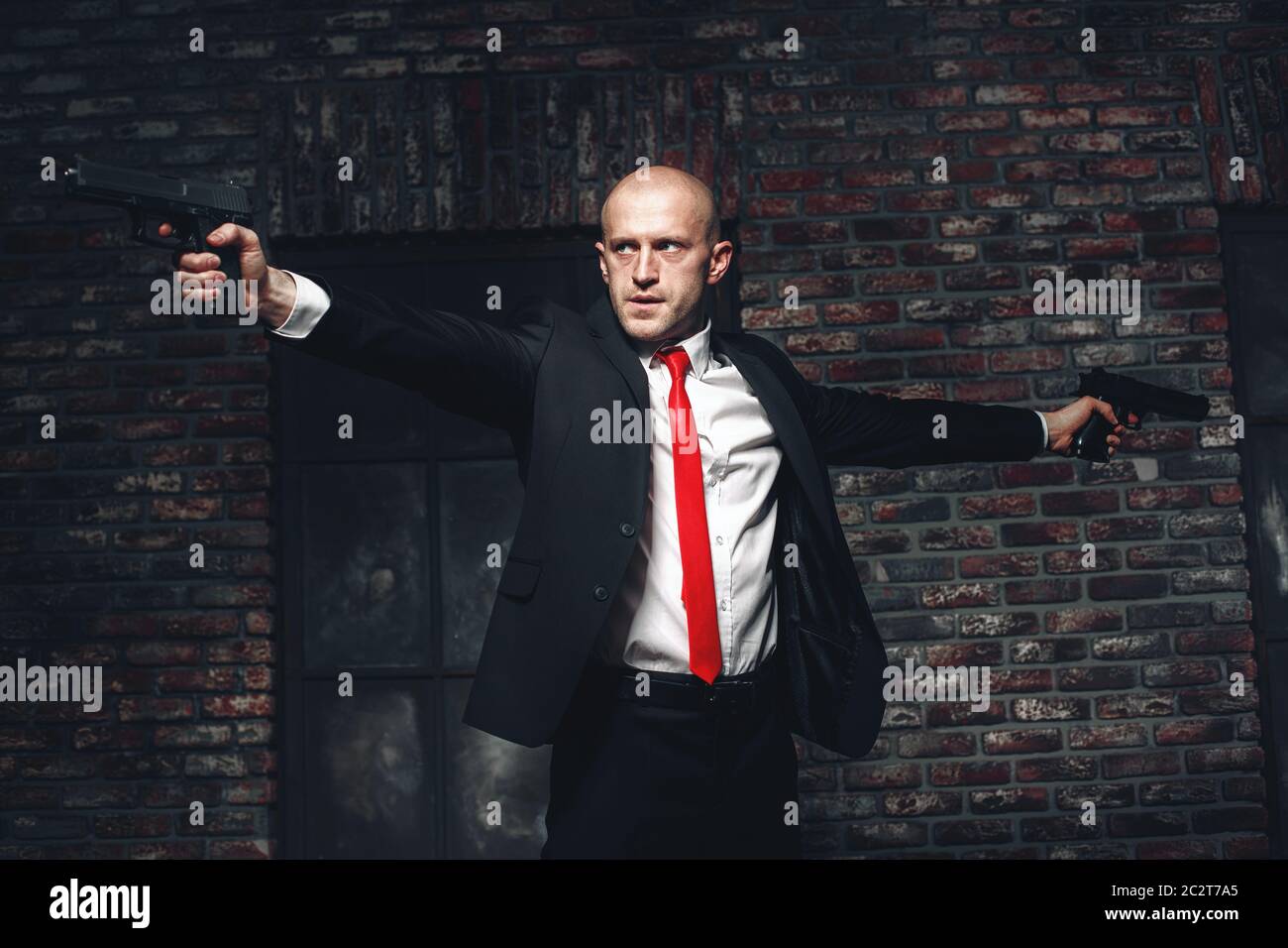Serious hired assasin in red tie aims with two pistols. Professional secret  agent concept. Murderer with guns, wallpaper, background or poster Stock  Photo - Alamy