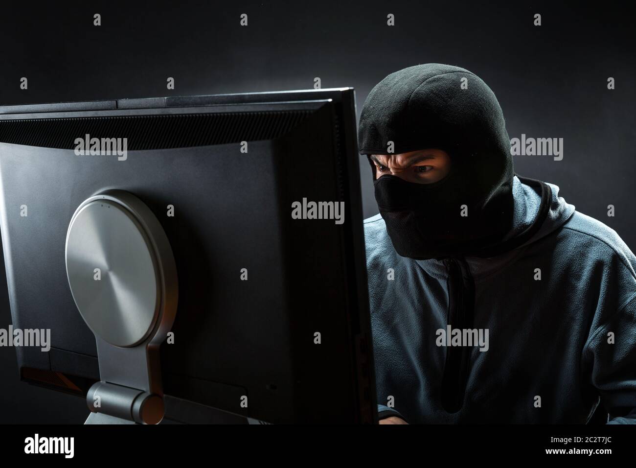Hacker in mask is stealing information Stock Photo