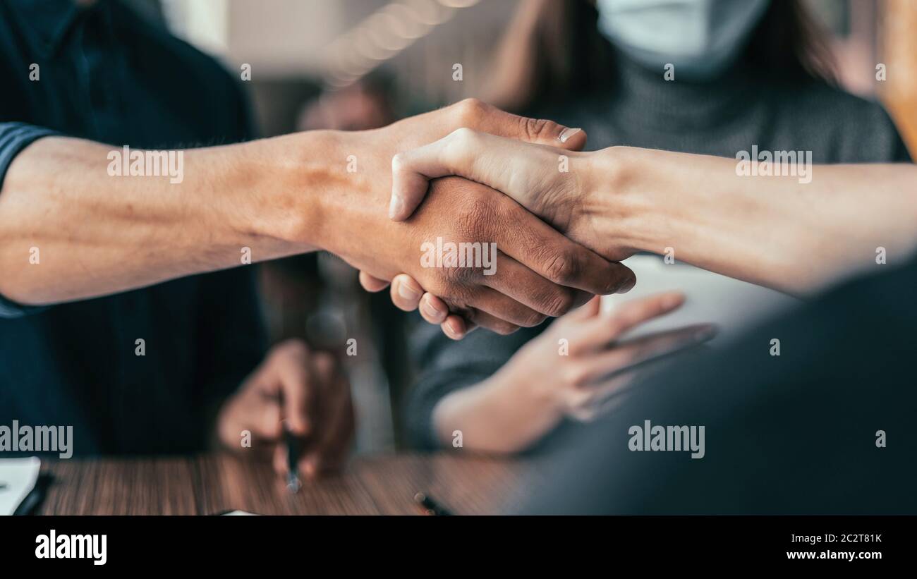 business man in a protective mask squeezing the hand of his colleague. Stock Photo