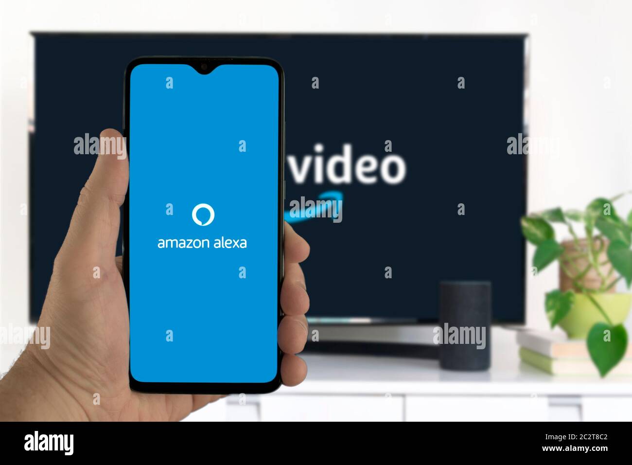 Hand holding a mobile with the Amazon Alexa app icon on it controlling some  home automation system and gadgets Stock Photo - Alamy