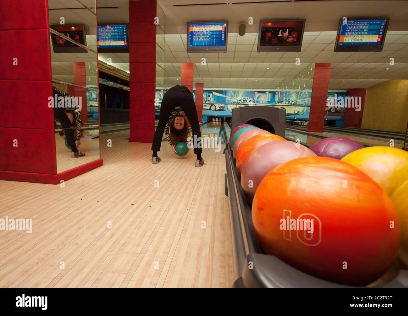 Funny beginner girl playing bowling. Wide angle Stock Photo - Alamy