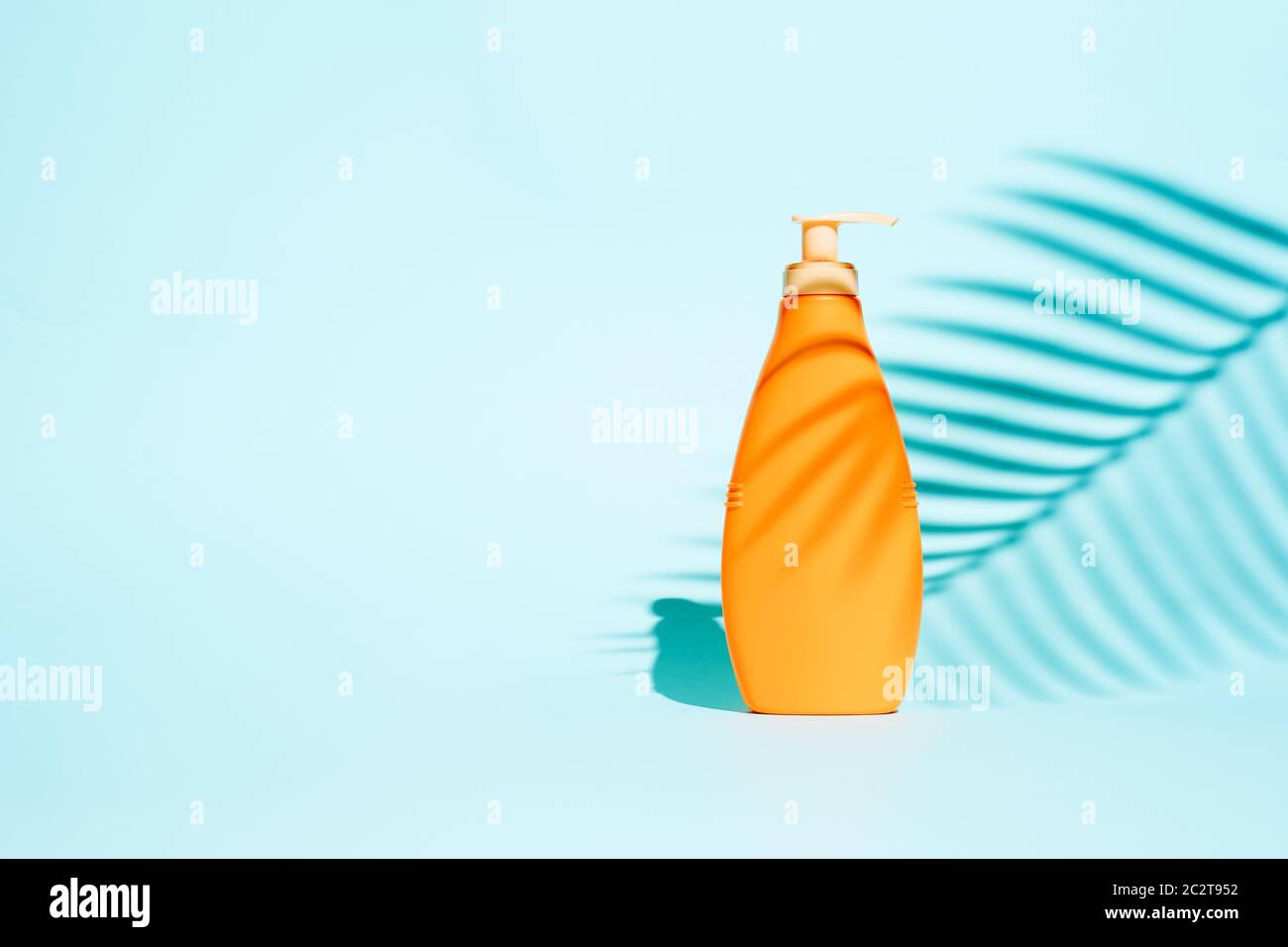Orange container for lotion without label on blue background with leaf, space for text Stock Photo