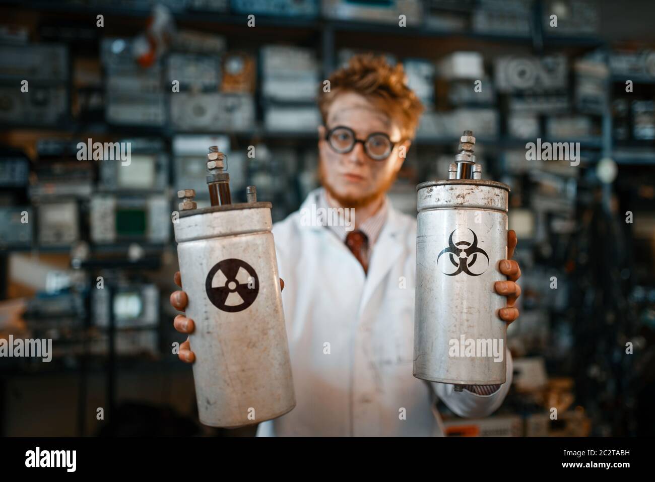 Strange scientist holds radiation materials in his hands, dangerous test in laboratory. Electrical testing tools on background. Lab equipment, enginee Stock Photo