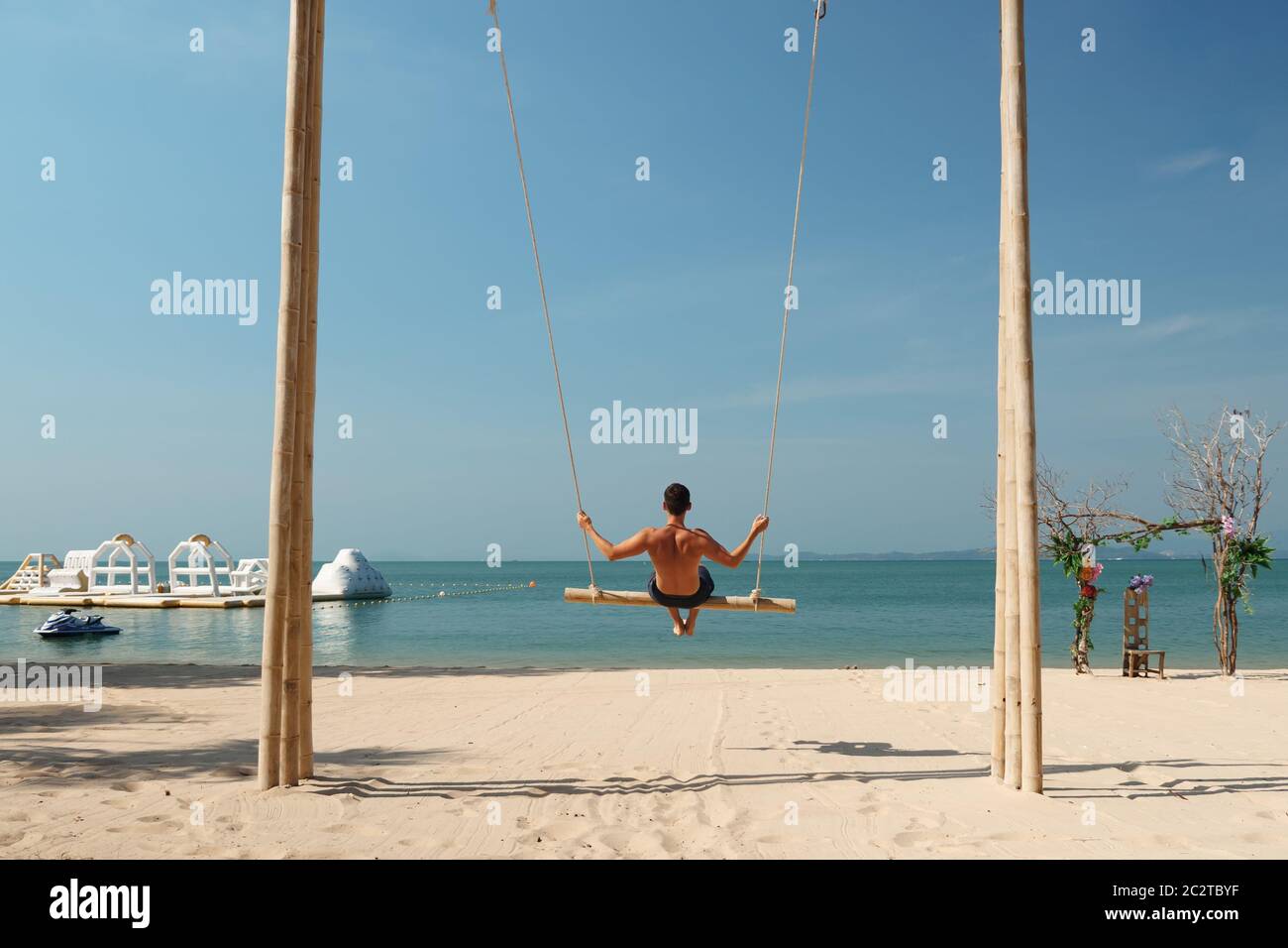 man swings on sand beach enjoying summer vacation on exotic resort