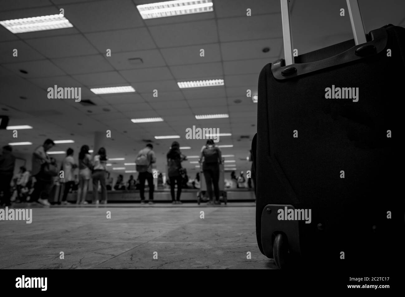 Closeup baggage on blurred people waiting for luggage on conveyor belt at baggage claim in the