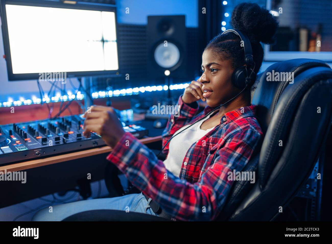 Female performer in headphones at the monitor in audio recording studio