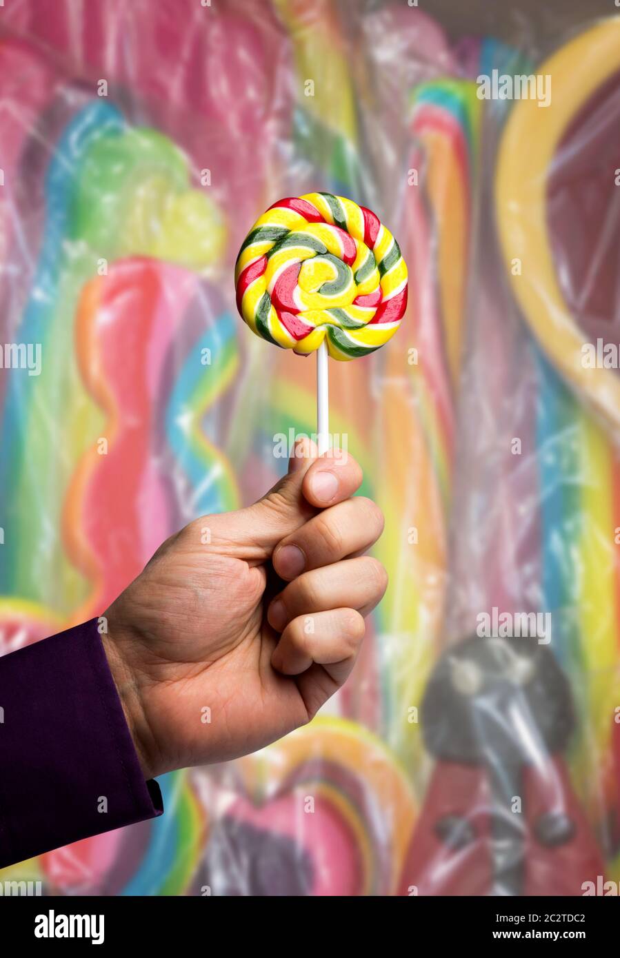 Male hand holding a multicolored lollipop Stock Photo