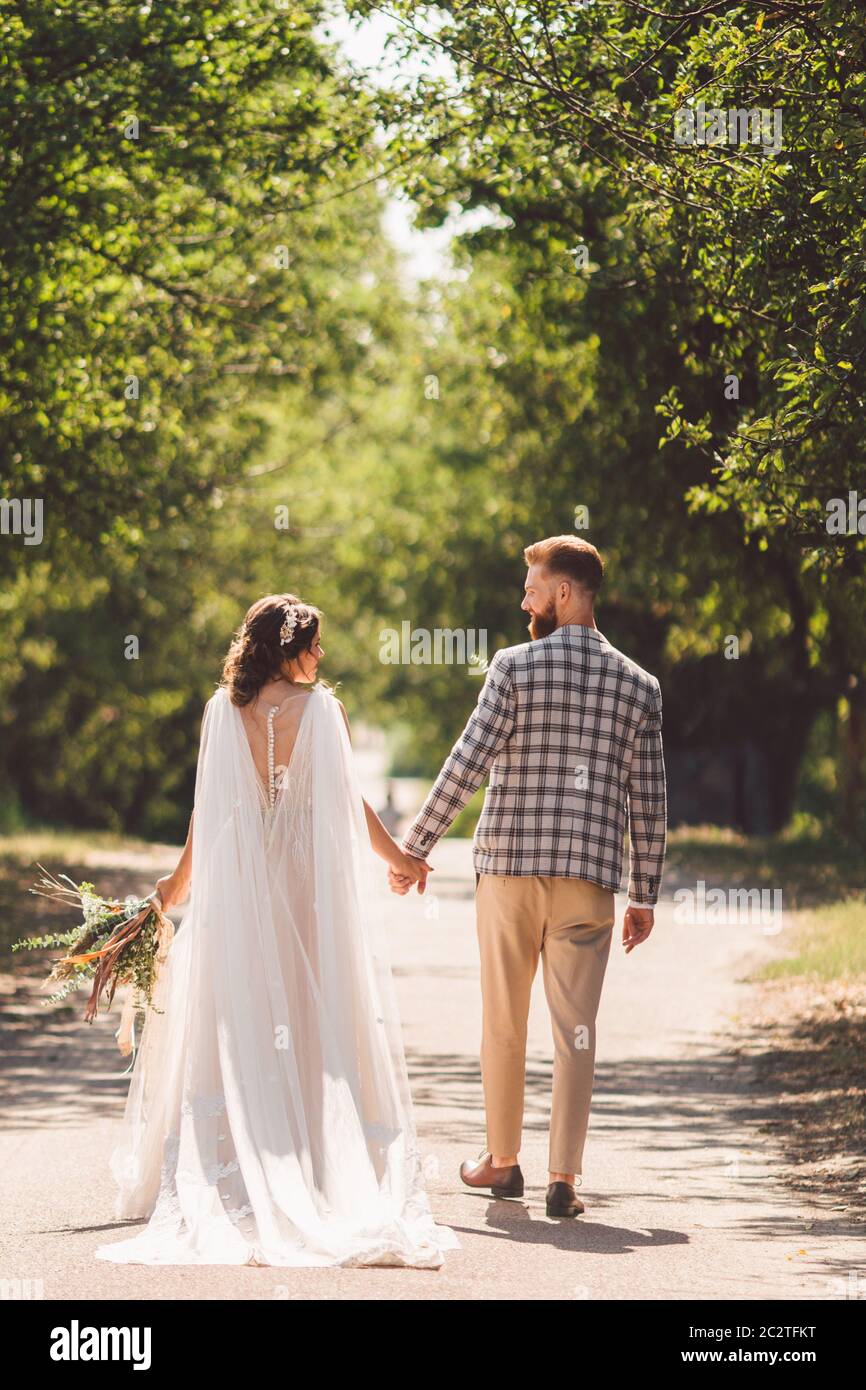 Happy bride and groom holding hands and walking in garden wedding day ...