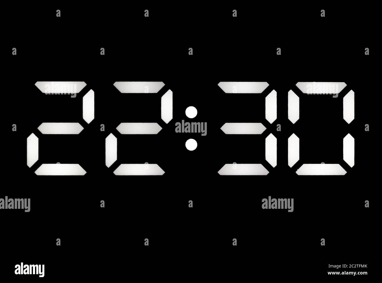 Real white led digital clock on a black background showing time 7 