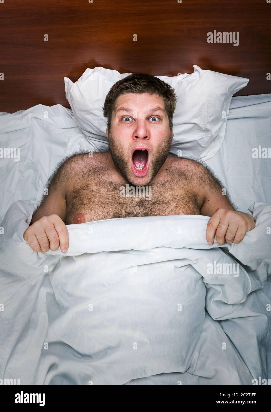 Top view of surprised man in white bed Stock Photo