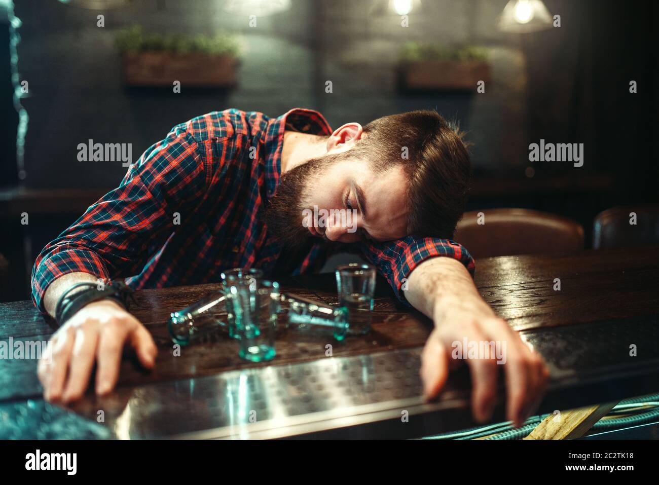 Drunk man sleeps at the bar counter, alcohol addiction. Male person in ...