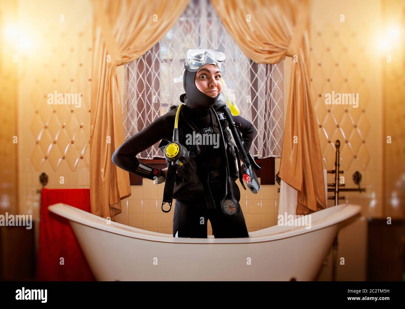 Female diver in wetsuit and diving gear is in the bath, bathroom