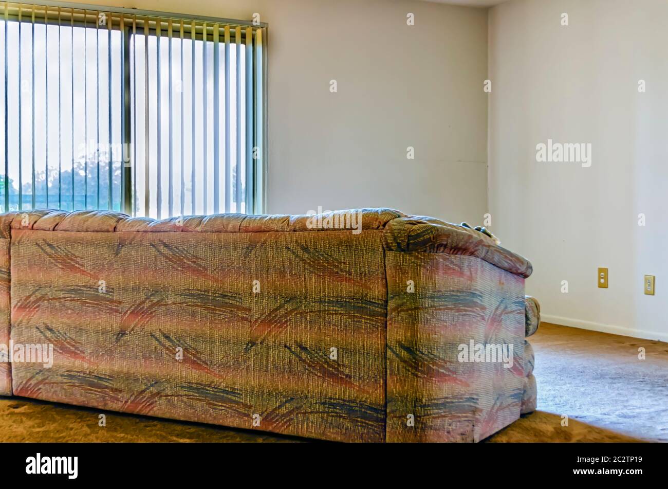 The back of an empty couch as it sits in an empty room. Stock Photo