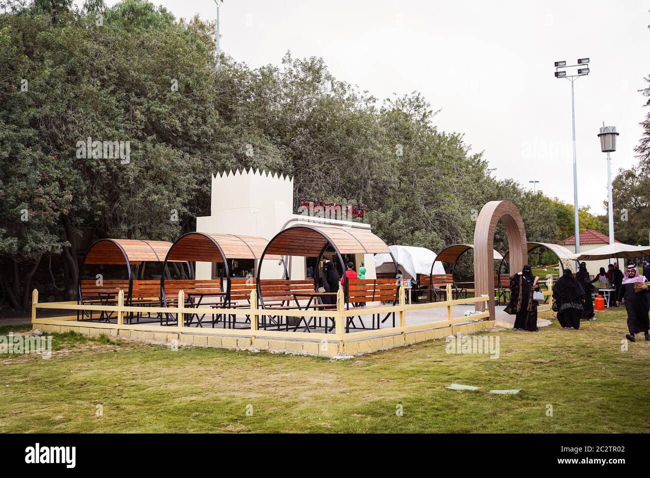 Abha / Saudi Arabia - January 23, 2020: Outdoor cafe with modern design and Saudi women wearing black abaya and niqab leaving only their eyes visible Stock Photo