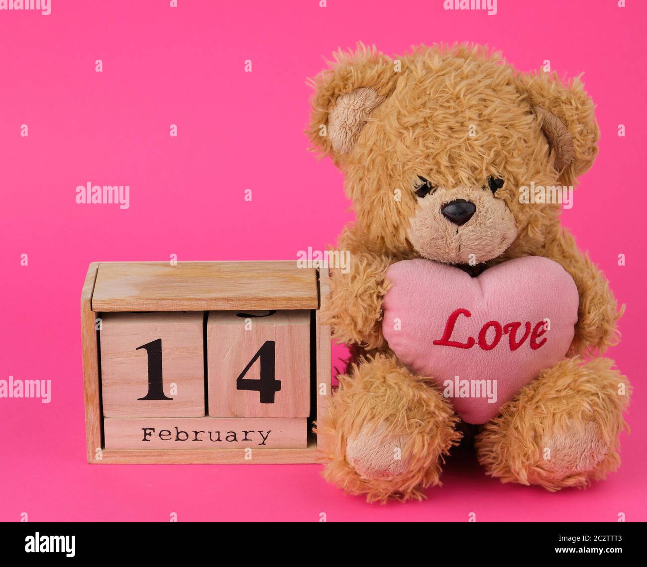 cute brown teddy bear holding a big red heart and wooden calendar with