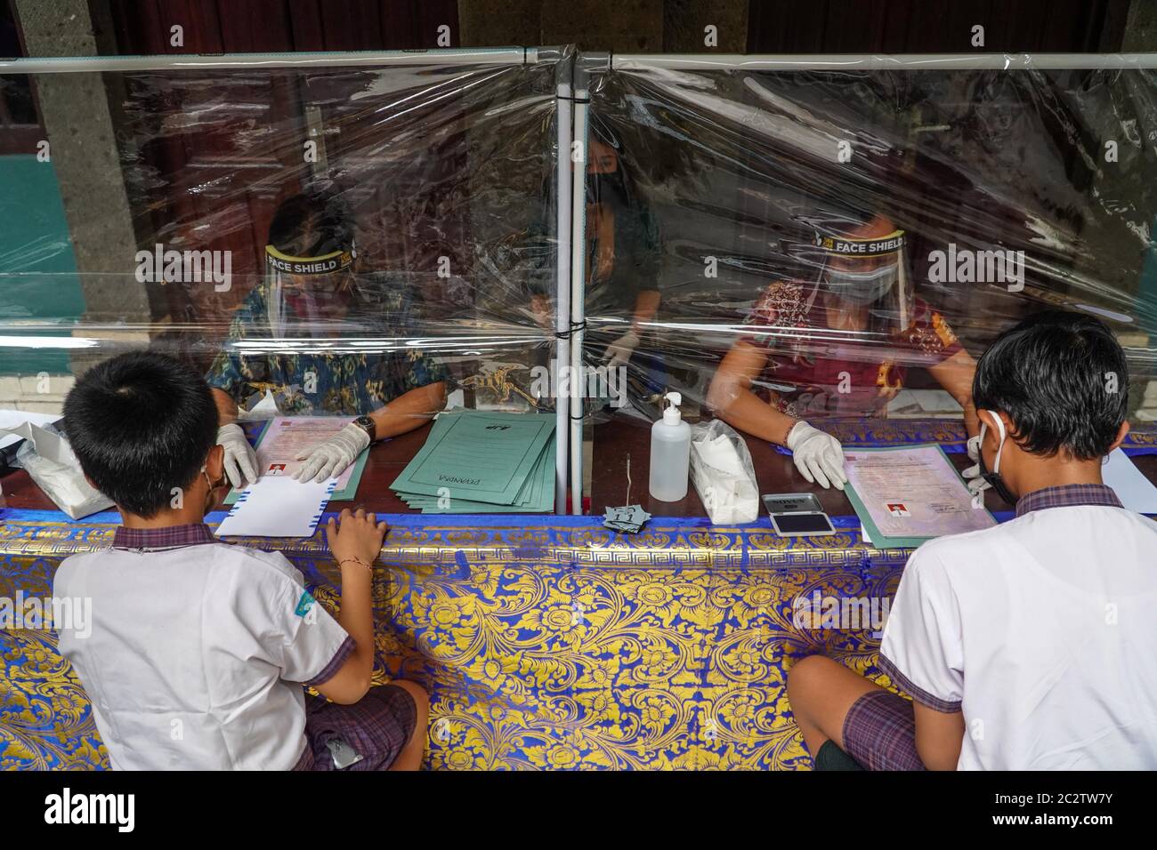 Badung, Bali, Indonesia. 17th June, 2020. Plastic shield divider separates school administrators and students. Widiatmika school of Jimbaran applying health protocols towards document management of their graduated students to prevent Covid-19 coronavirus for further spreading. (Credit Image: © Dicky BisinglasiZUMA Wire) Stock Photo