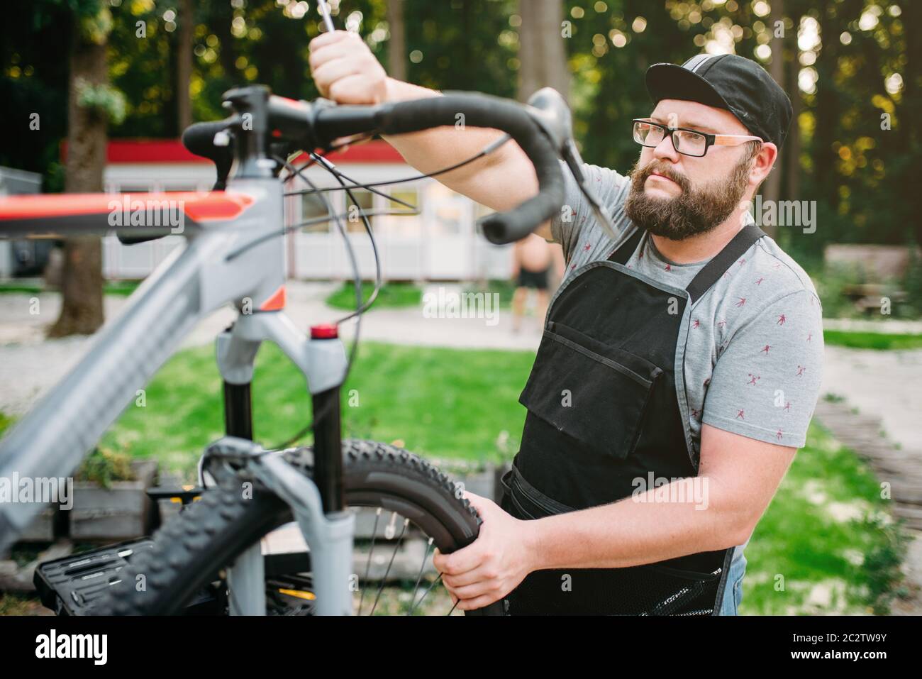 Bicycle mechanic repair bike, top view. Cycle workshop outdoor. Bicycling sport, bearded service man work with wheel Stock Photo