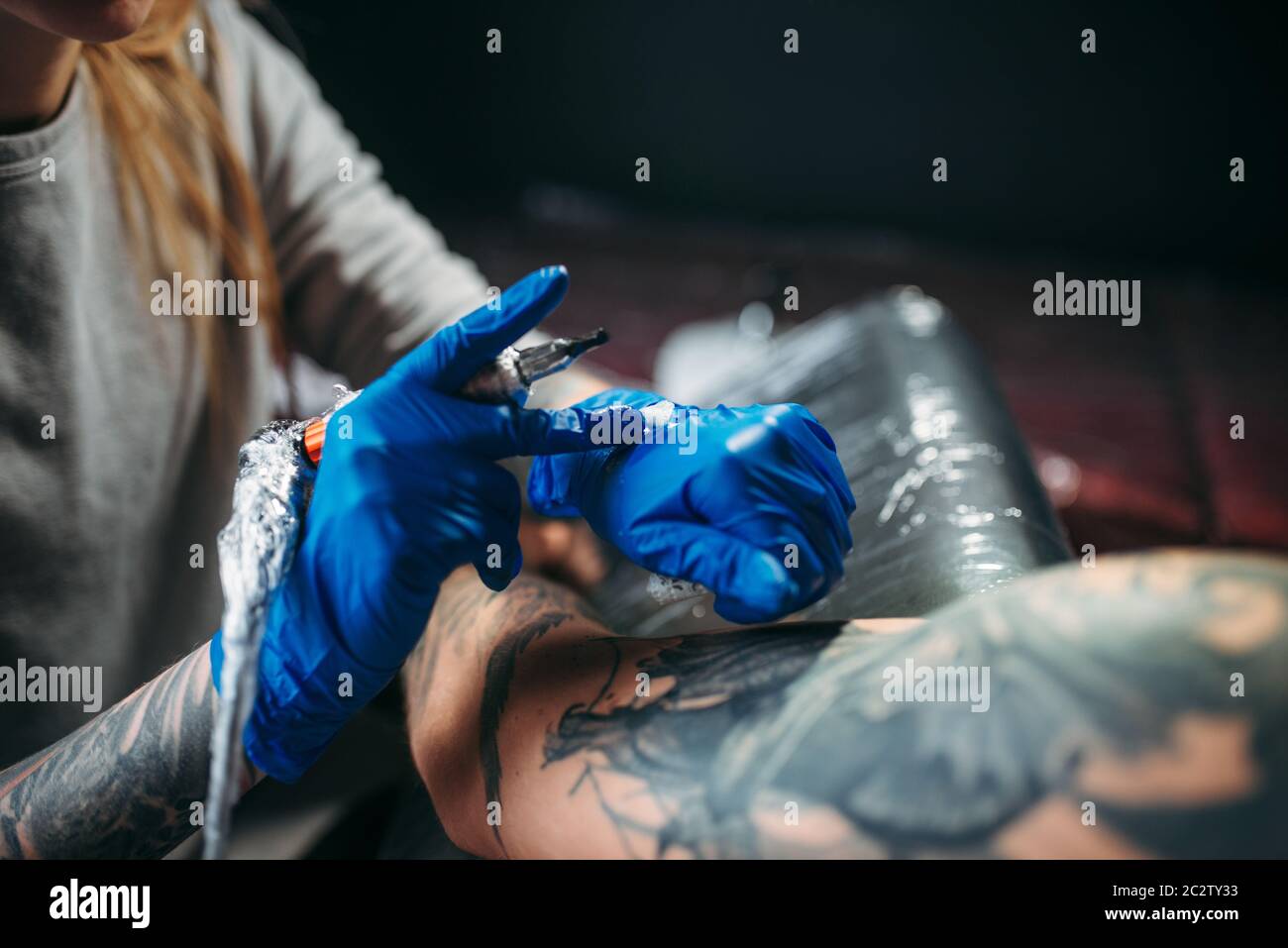 Female tattooist makes tattoo by machine on the shoulder. Professional