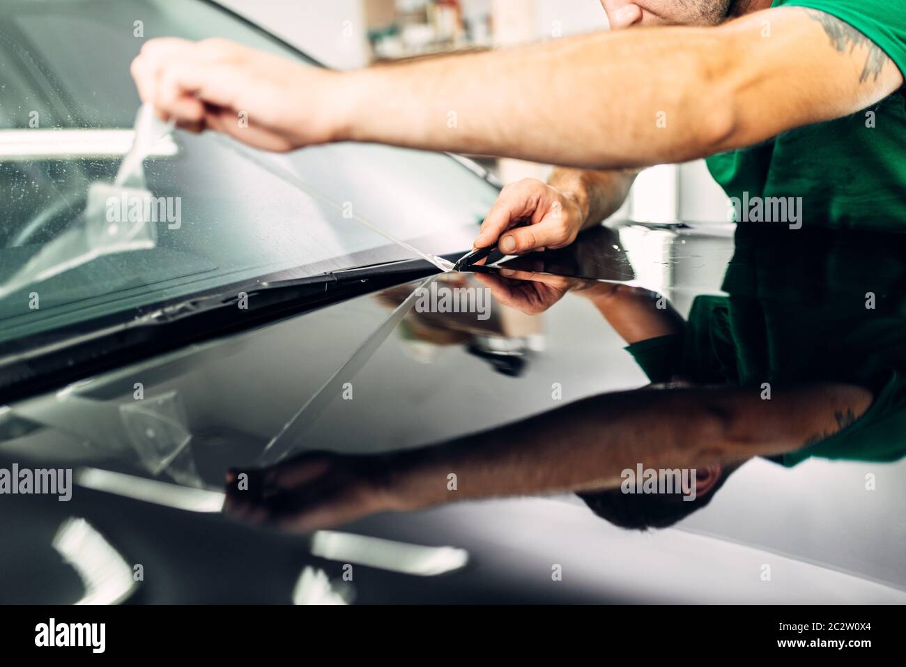 Man installs car paint protection film on hood. Transparent protective