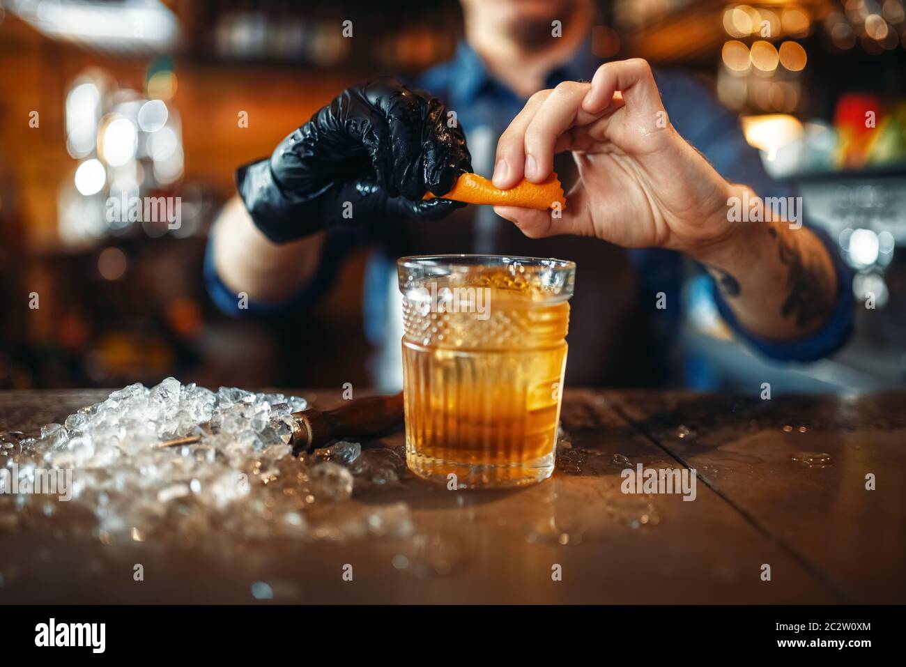 Male bartender adds orange skins to an alcoholic beverage at the bar ...